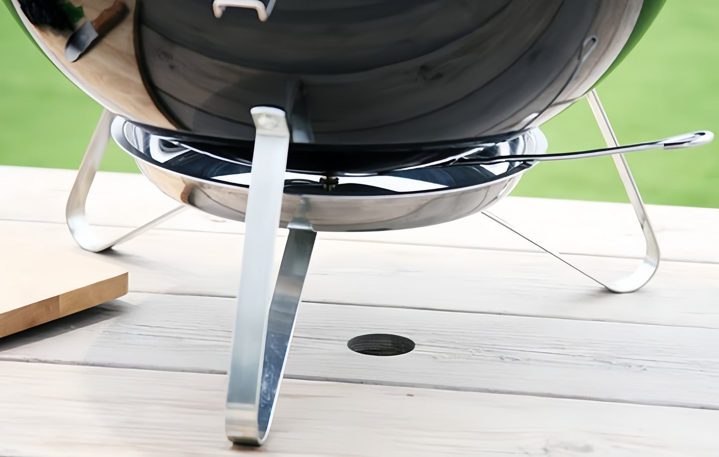 Détail du piètement métallique stable du barbecue portable posé sur une surface plane.