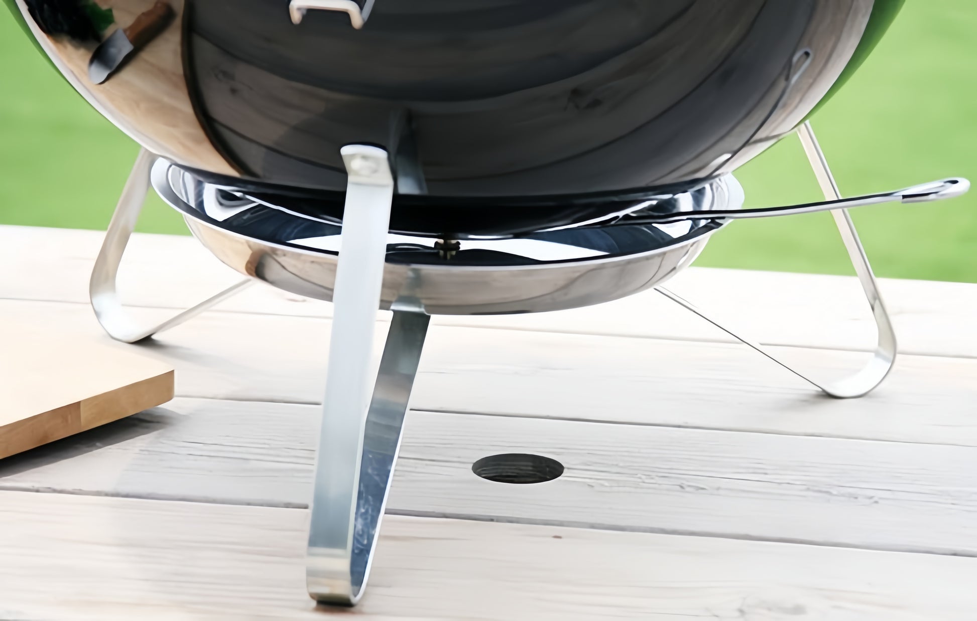 Détail du piètement métallique stable du barbecue portable posé sur une surface plane.