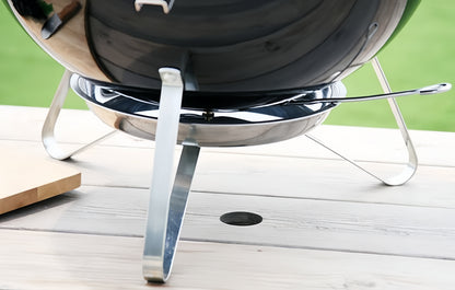 Détail du piètement métallique stable du barbecue portable posé sur une surface plane.