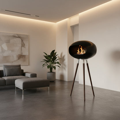 Cheminée éthanol design COCON PURE grand noir mat profond sur pieds scandinaves hauts, installée dans un salon contemporain minimaliste, flamme décorative élégante et chaleureuse.