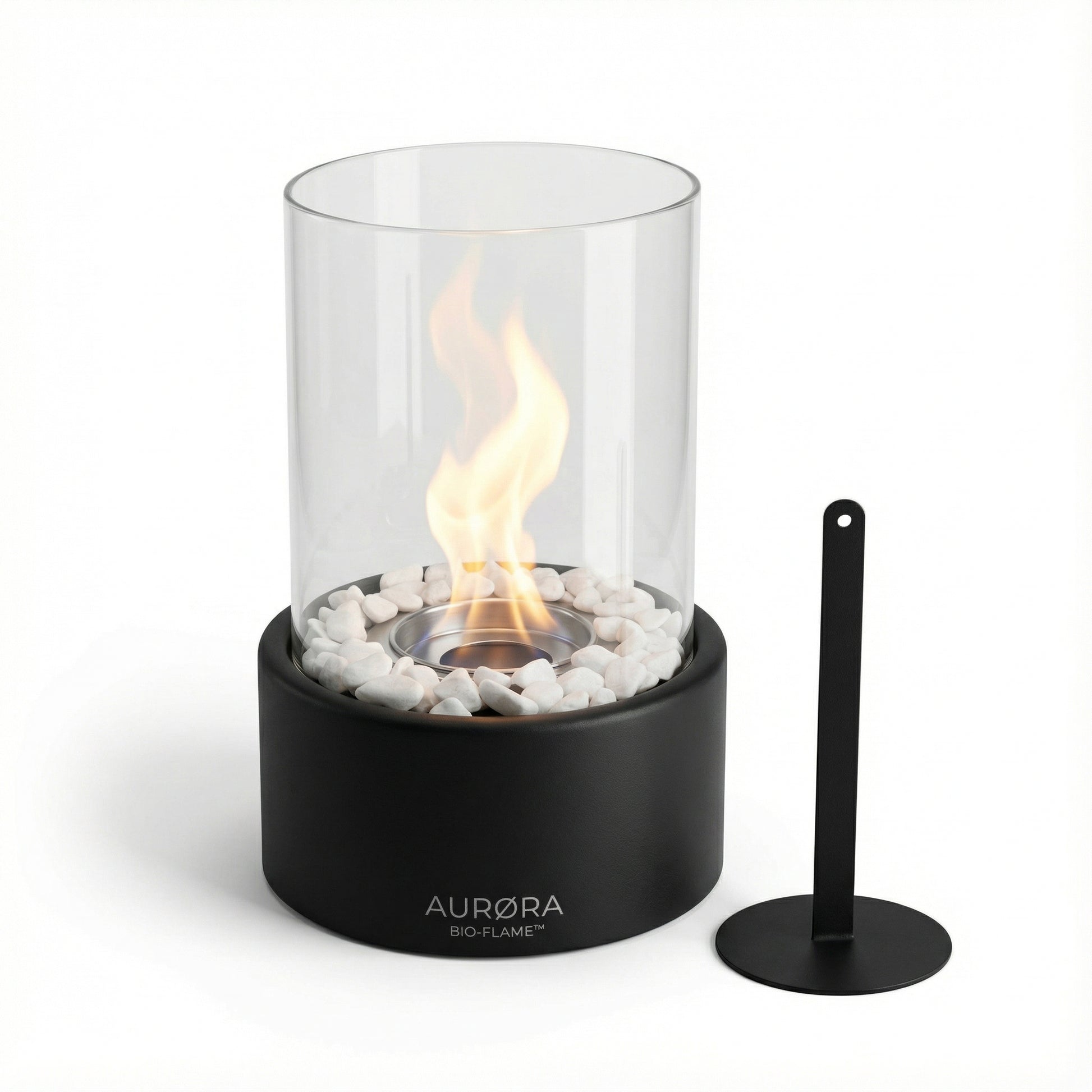 Foyer de table cylindrique noir en acier et verre borosilicate avec sa flamme et son outil d'extinction minimaliste sur fond blanc.